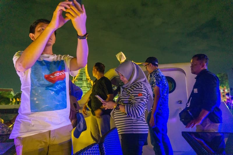 tourists taking photos on the chao phraya river cruise in bangkok