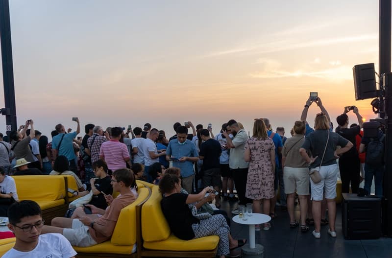 crowds gather on the roof of the maha nakhon skyealk in bangkok at sunset