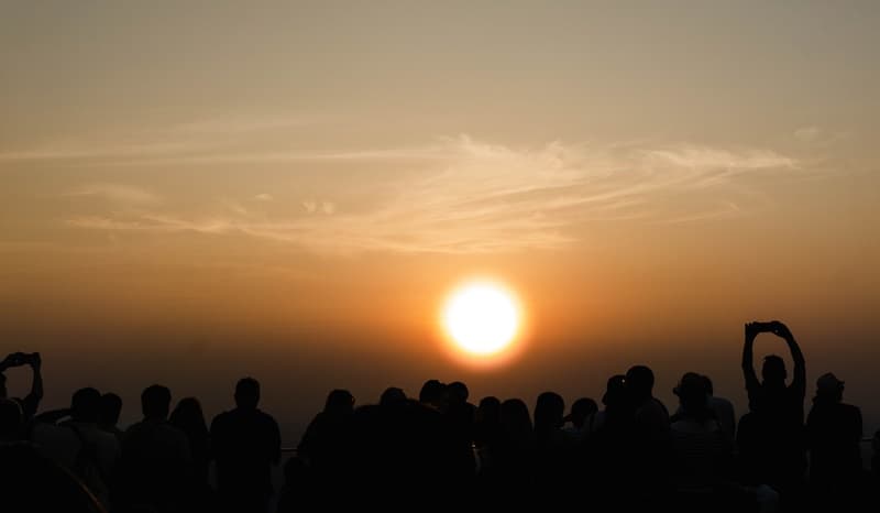siloute of tourists on the Maha Nakhon building taking pictures of the sunset