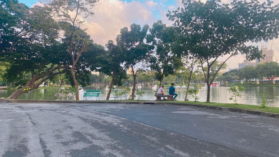 people sitting on the park bench in Lumpini Park Bangkok next to lake