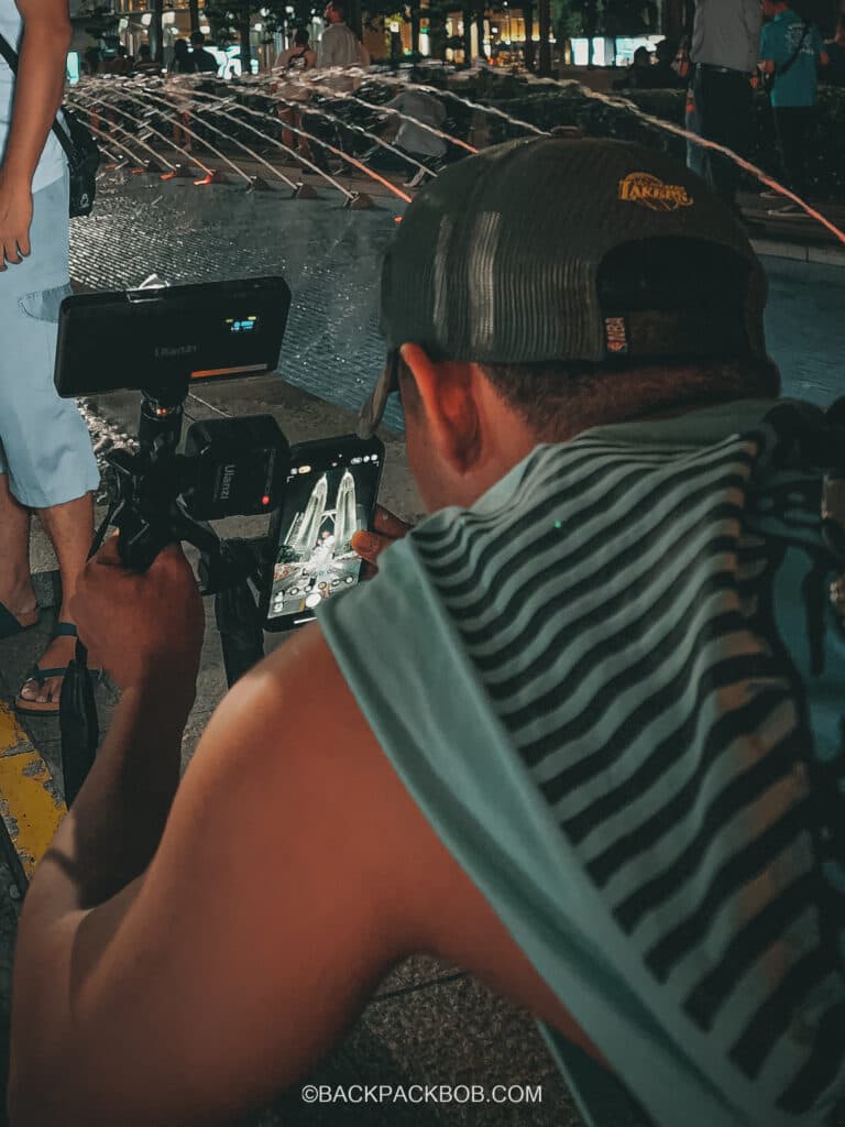 A local Malaysian Man takes a photo of tourists outside the Petronas Towers in Kuala Lumpur