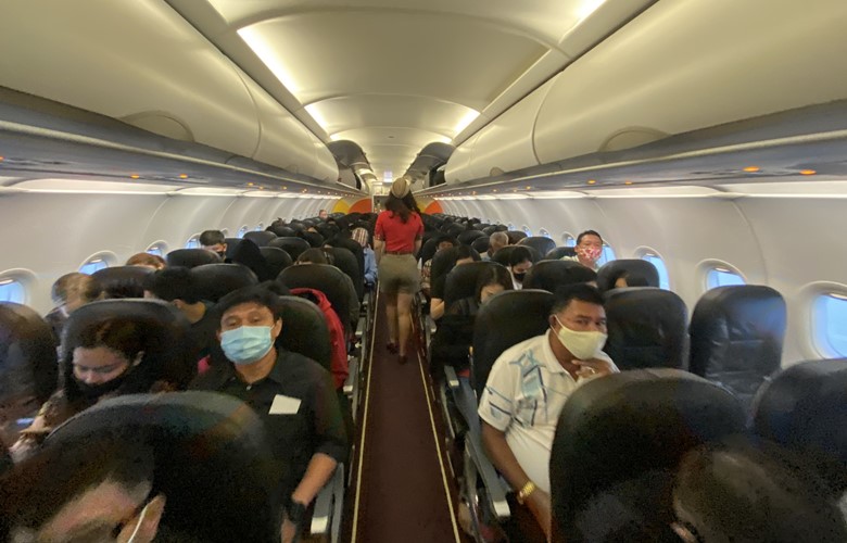 flight attendent leading passengers to seat on a flight during the covid pandemic