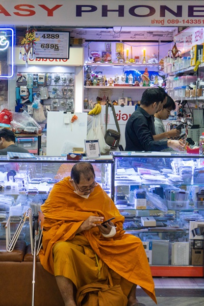 Monk has his mobile phone repaired at the MBK Center in Bangkok