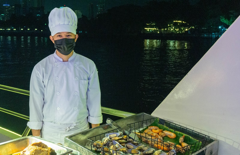 chef on board the bangkok dinner cruise serving steak king prawns and muscles