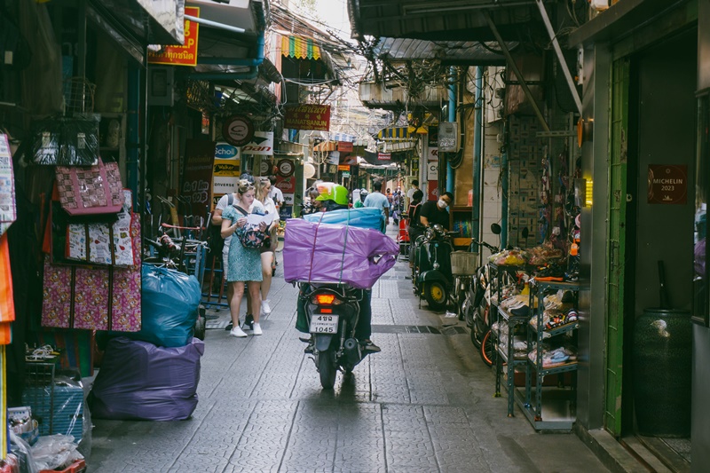 tourist read map in china town bangkok on narrow alley as motorcycle rides past