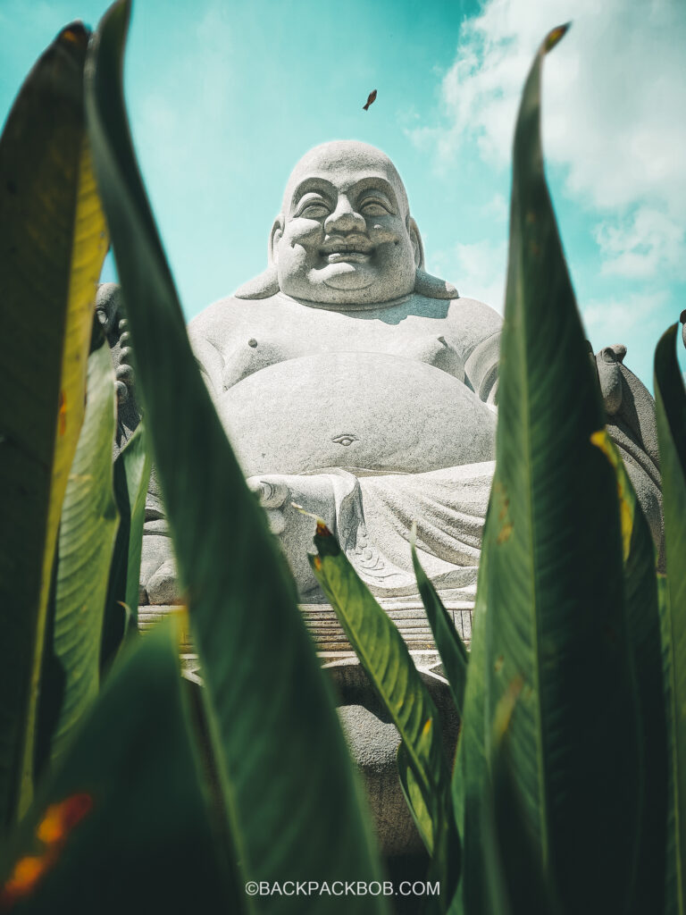 Ipoh Buddhist Statue at temple, a small bird flies overhead