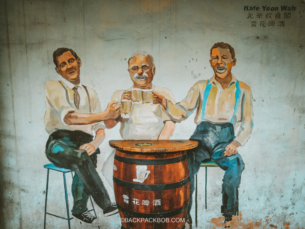 street art pictures three men drinking pints of beer around a barrel painted on the wall in Ipoh