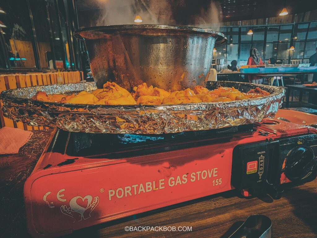 a steamboat dinner is a must on a Malaysia itinerary there is a portable stove cooking meats and soup on the eating table