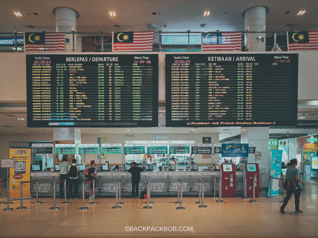 A departure board in the Kuala Lumpur bus terminal shows a list of the cheapest day tours and places you can get to from Kuala Lumpur