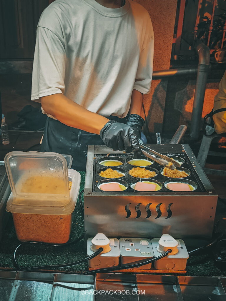 A seller cooks chinese egg burger at his sales booth on Jonker Street Market Jonkers Street Market | Jonkers Street Weekend Market | Jonkers Street Night Market | Jonkers Street Market in Melaka