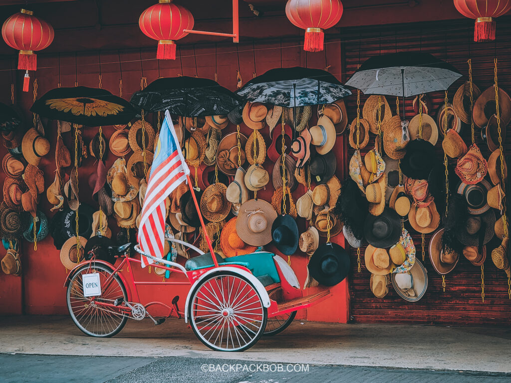 A photo of a red rickshaw next to a Kuala Lumpur tourist attraction