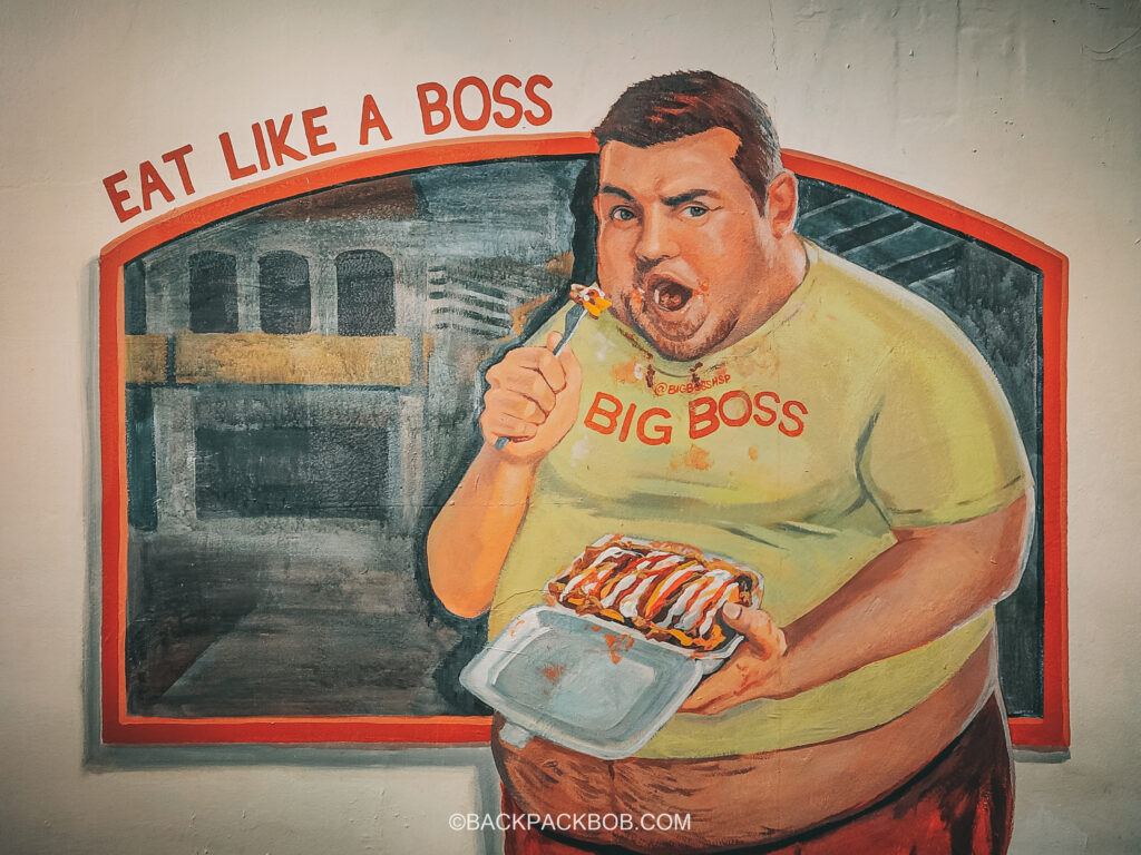Street Art which is free to view all around Kuala Lumpur city, the photos shows a painting of an overweigt man eating free things to do in Kuala Lumpur and typical Malaysian food