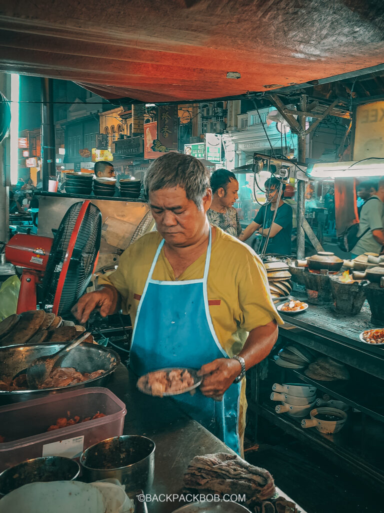 a chef cooks cheap street food at claypot restaurant free things hawker in malaysia man blue apron