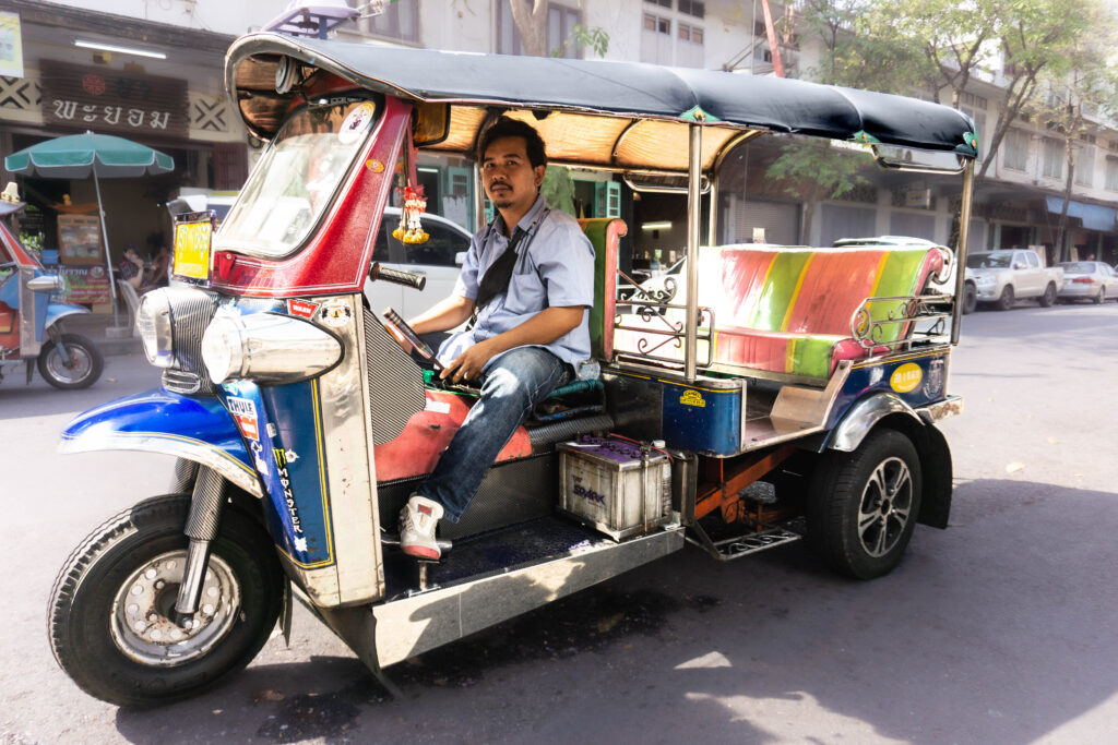 A Tuk Tuk driver is waiting for passengers outside the BTS Station