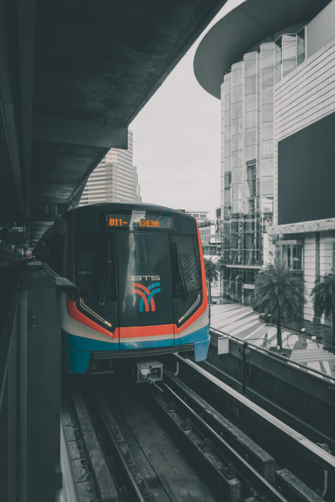 A BTS Skytrain leaving the station with Siam Paragon Shopping mall in the background