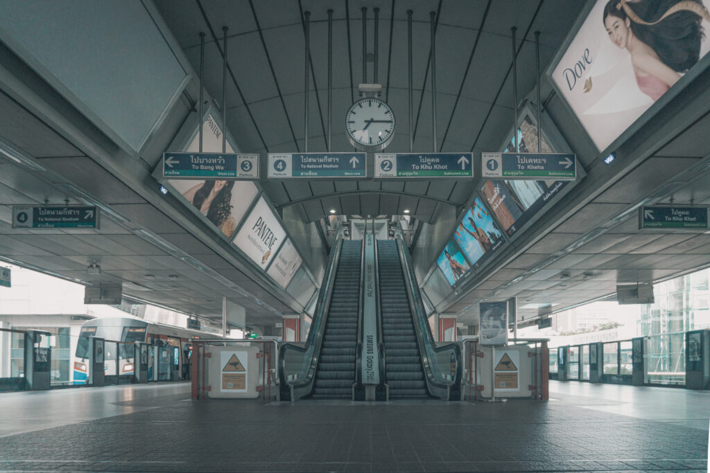 Siam Central BTS Train Station with escalators and large clock the are signs to the skytrain platforms and there are no passengers in the station a skytrain is on platform 3