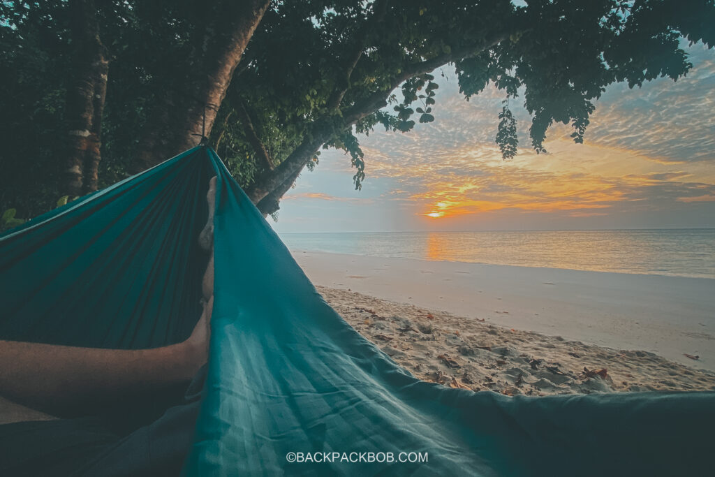 Relaxing in a hammock on the beach at sunset, at Pawapi Beach Resort in Koh Mook