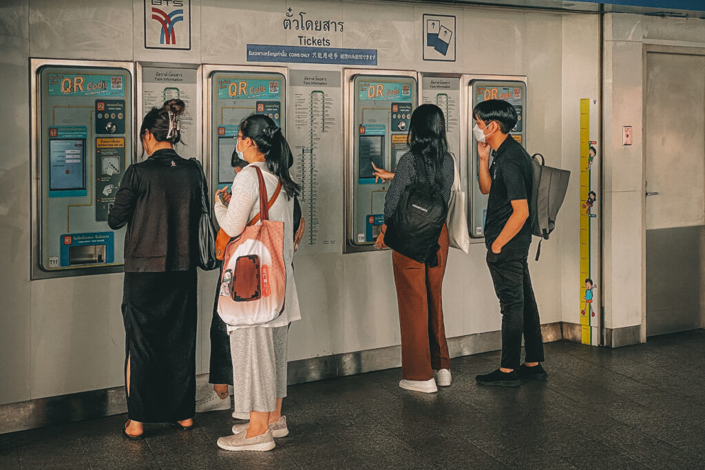 Passengers at Phrom Pong BTS Station que and learn how to use the BTS ticket machine to but tickets for the skytrain with prices