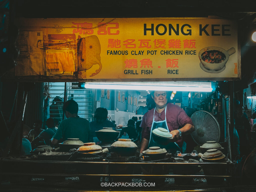 A chef cooks chicken clay pot in a Kuala Lumpur Hakwer cart it is free to sit but a meal costs 40 MYR, show on the sign