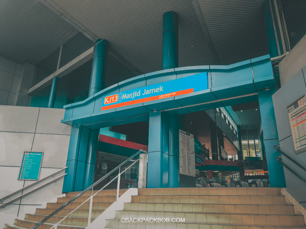 a Typical Train Station entrance in Kuala Lumpur, the station name is KJ13 and there is a blue archway to enter the station