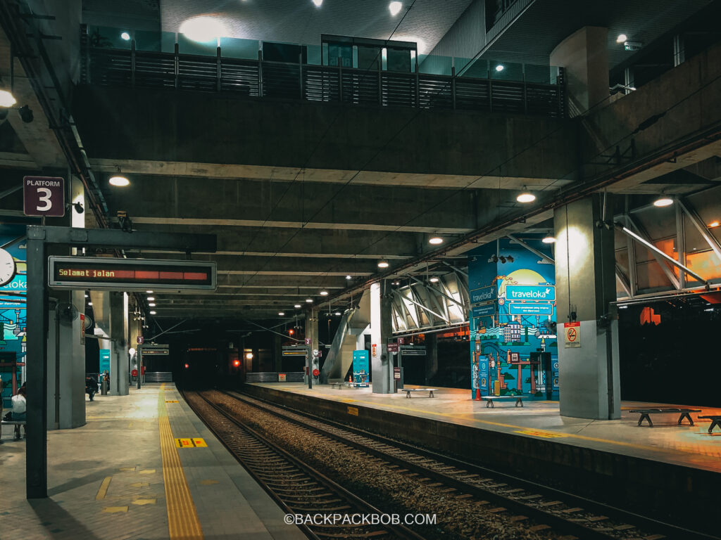 Putrajaya Train Station in Kuala Lumpur, the photo is taken outdoors at the train platform and the sign displays information about arrivals and departure to KLIA Airport