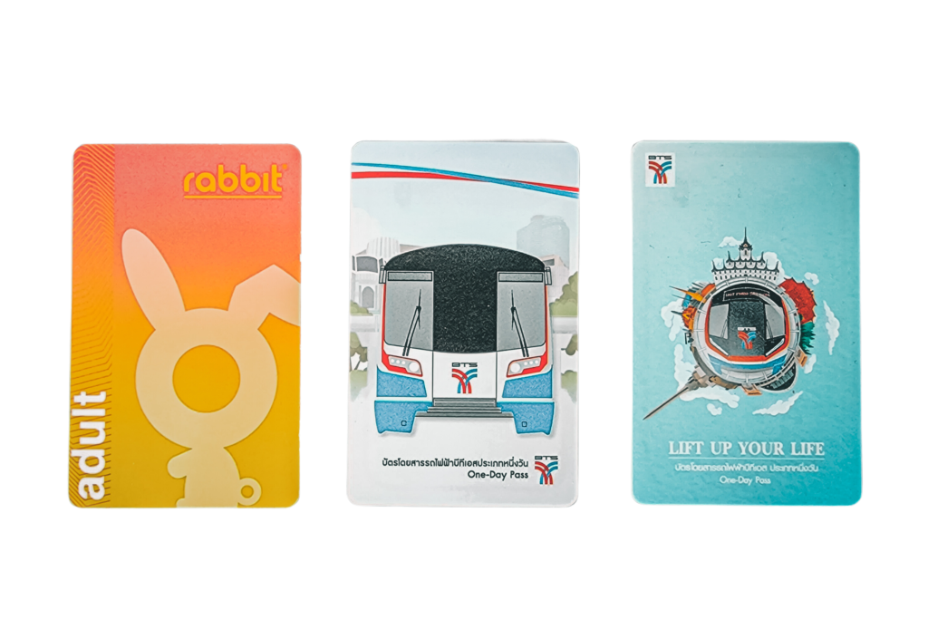 A photo of three types of BTS Skytrain tickets there is a one-day tourist pass, a Rabbit Card nd a single journey Skytrain ticket